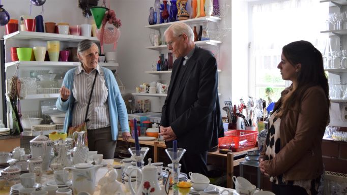 Gerdi Breuksch (l.) zeigt Weihbischof Dr. Nikolaus Schwerdtfeger das Angebot im FAIRKAUF-Laden der Caritas Südniedersachsen und berichtet über die Arbeit des Laden-Teams. | Foto: Johannes Broermann / cps