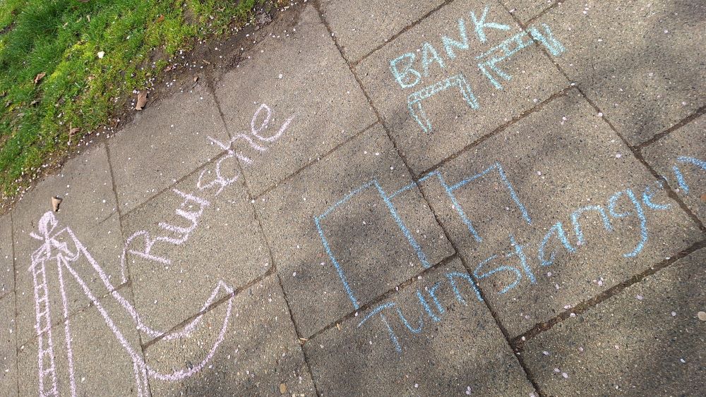 Mit Kreide auf den Gehweg gezeichnete Wünsche für einen neuen Spielplatz.